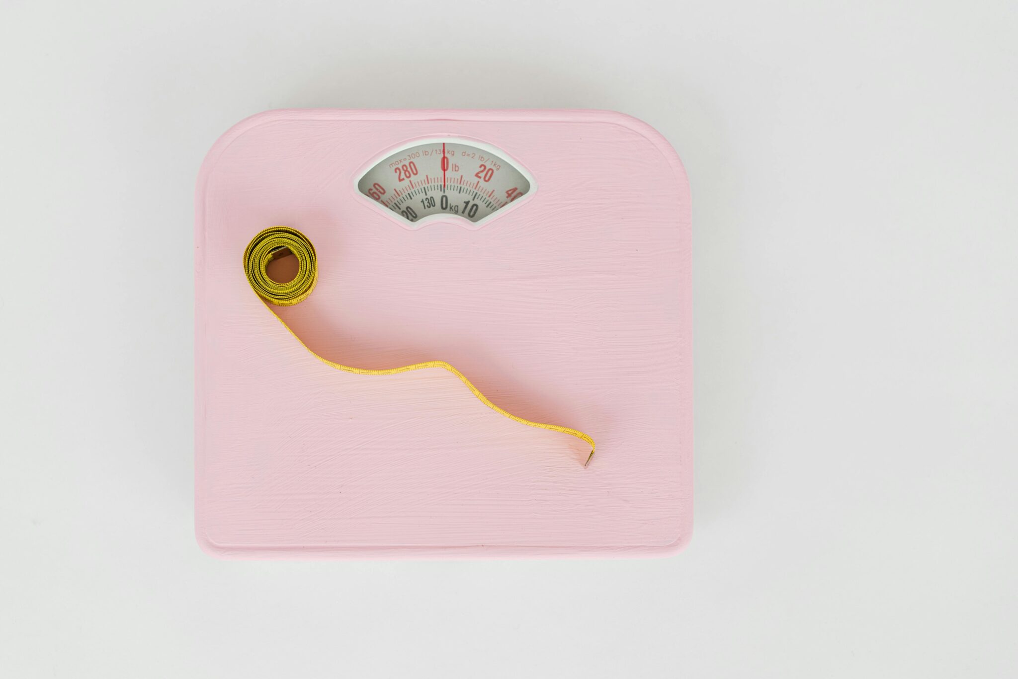 Top view of floor scales for weight control and measuring tape for controlling body shapes on white background